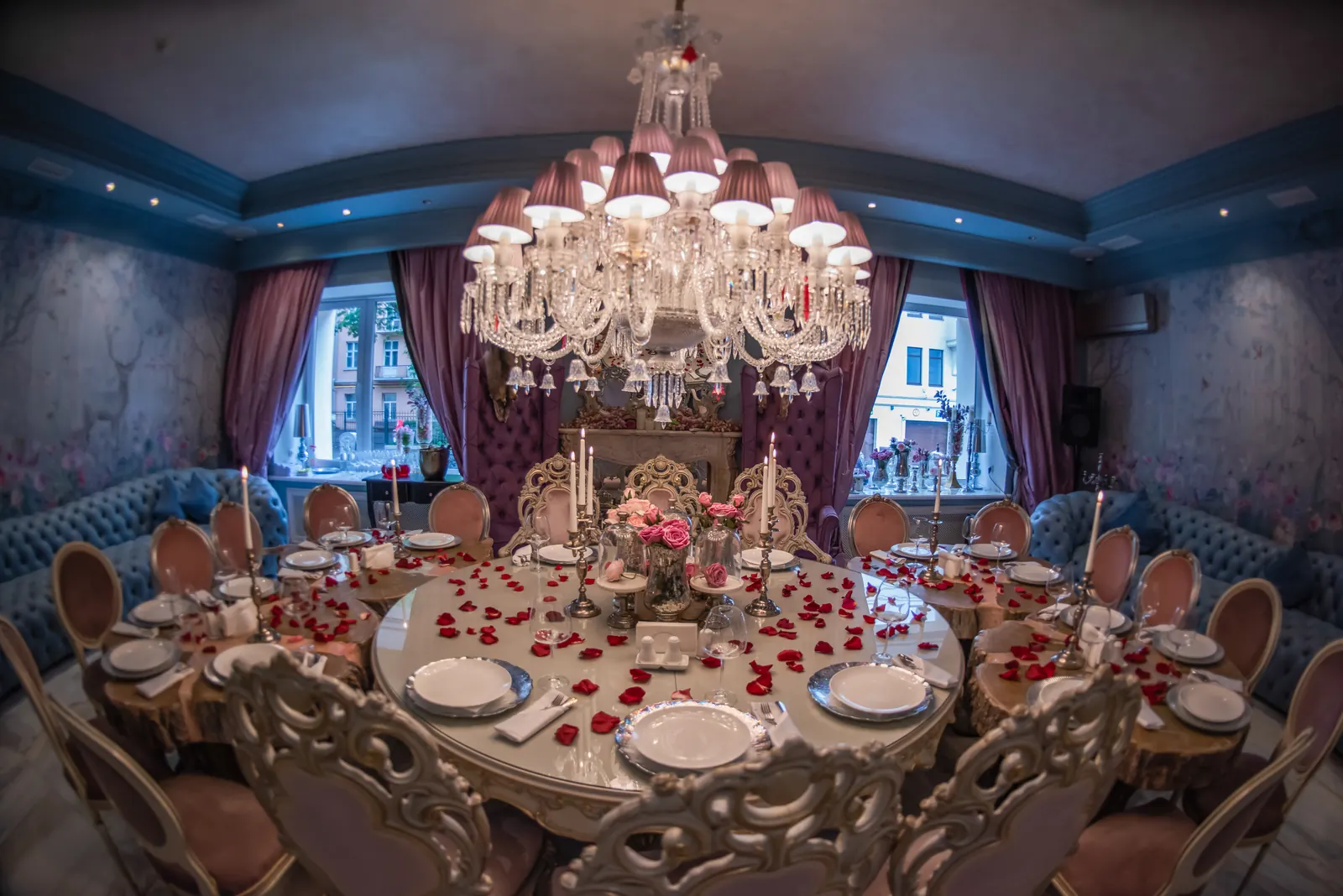 A round banquet table set for a dinner under a chandelier.