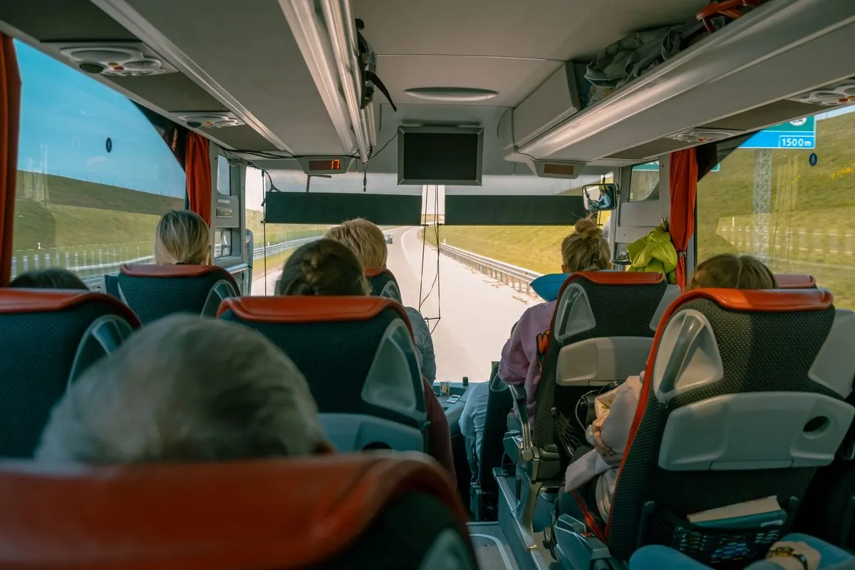 Passengers seated in the cabin of a touring coach on a highway.