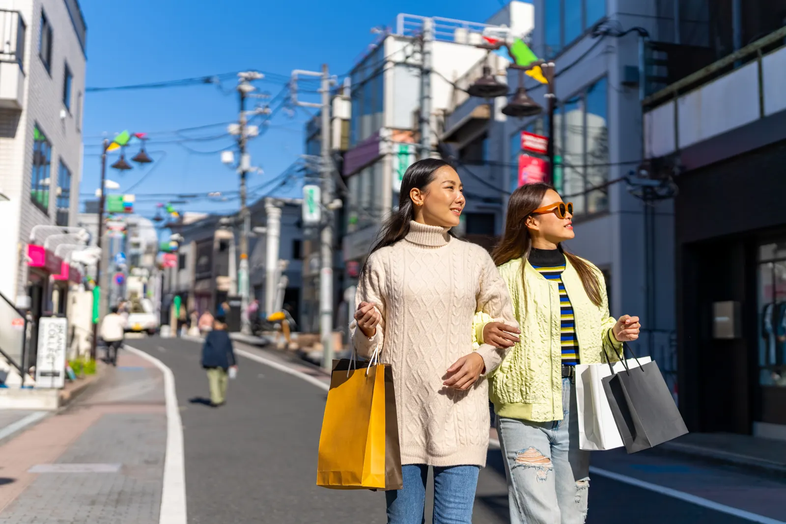 Friends carrying shopping bags on a city street in Tokyo.