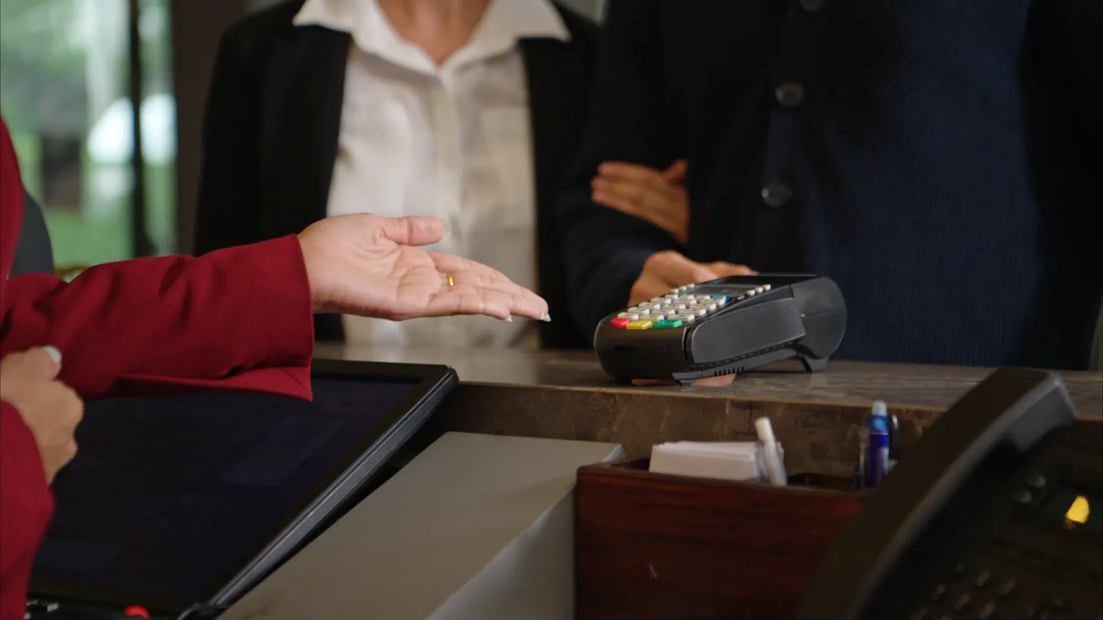 A guest pays with a card at a hotel reception desk.