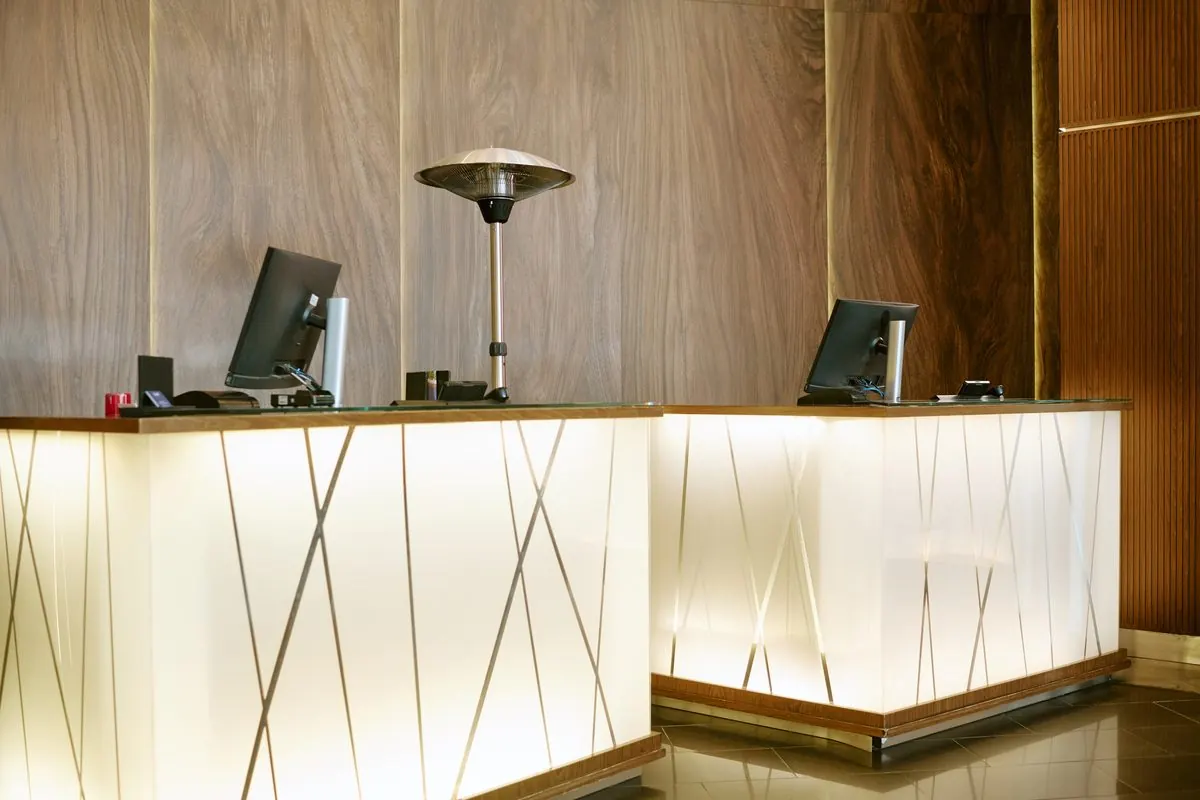 A hotel reception desk lit from below, with wood panels behind.