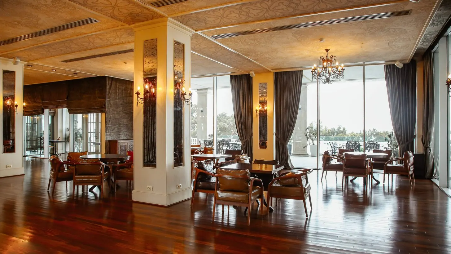 A hotel restaurant with armchairs and tall windows.