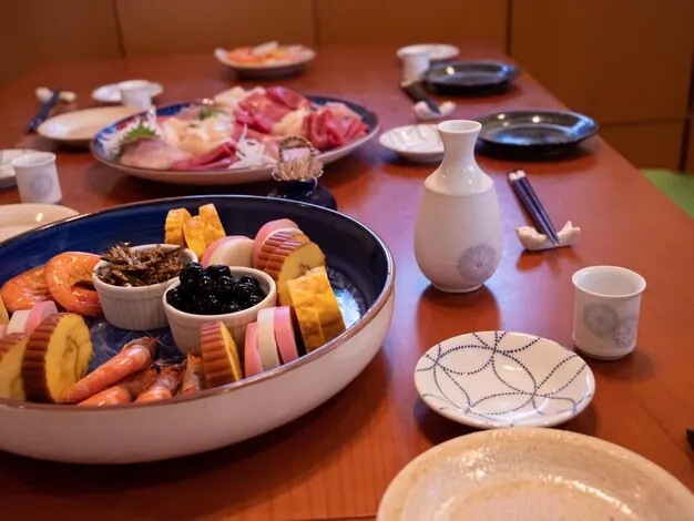 A table set with sashimi, small dishes and sake cups.