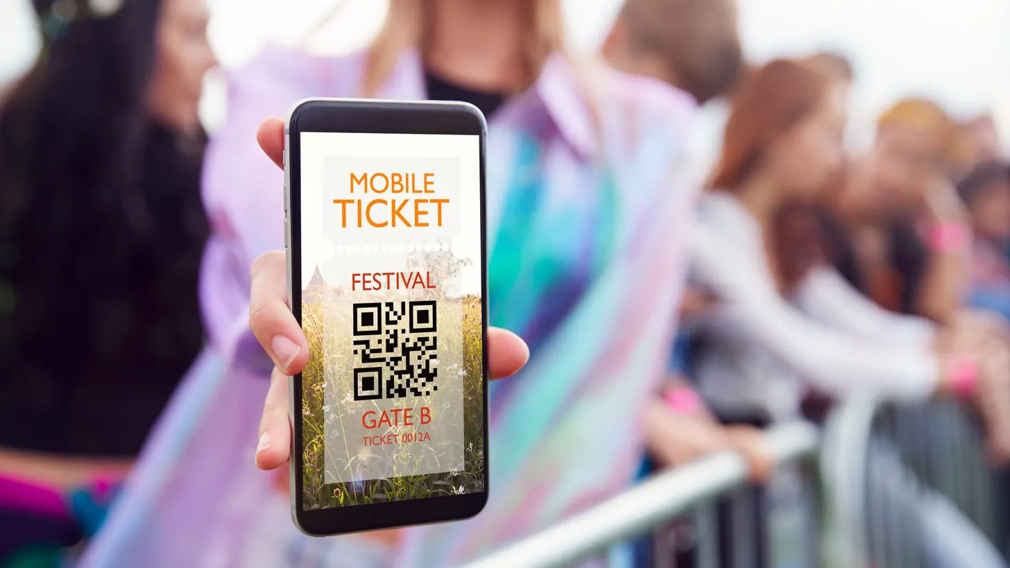 A phone showing a mobile ticket with a QR code at an event entrance.