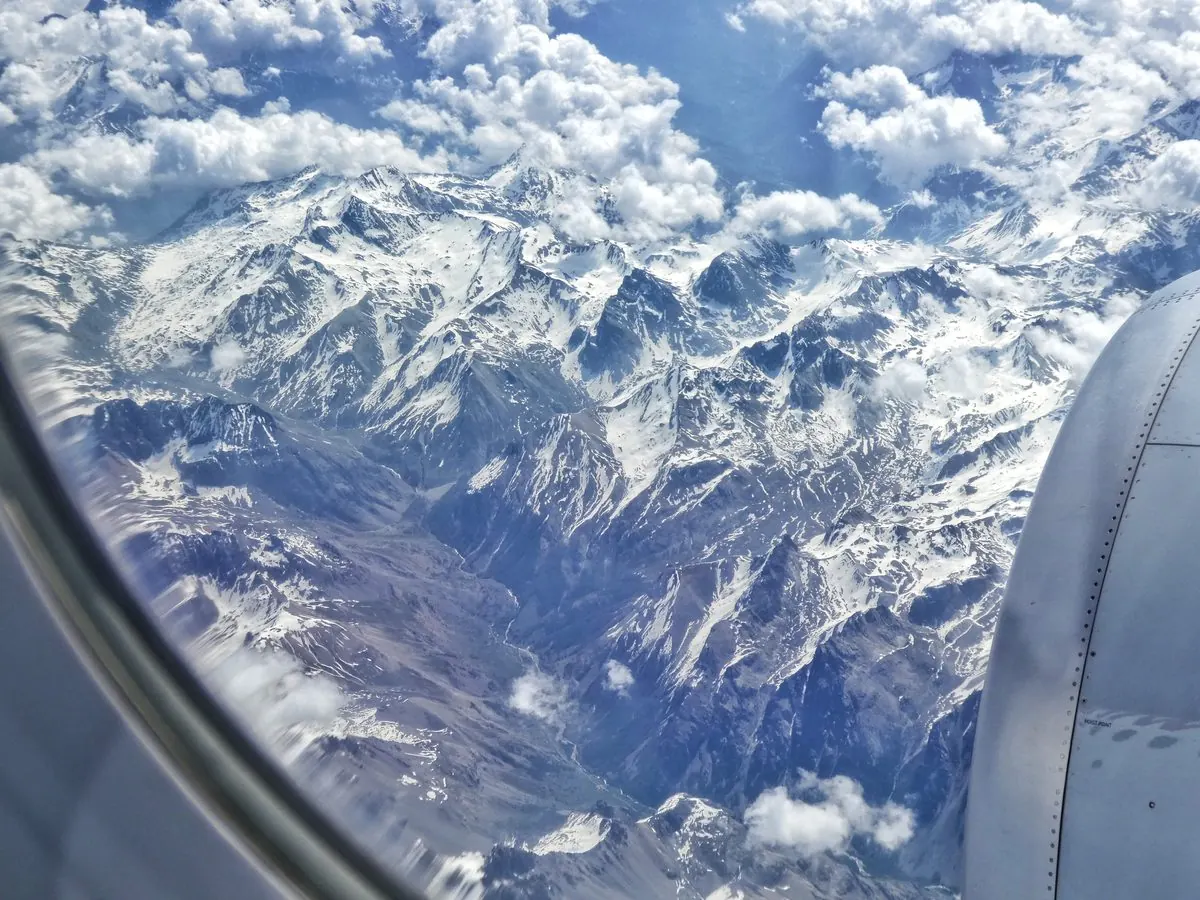 Snow-capped mountains seen through an aircraft window.