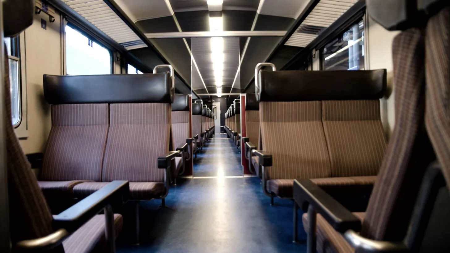 Rows of upholstered seats along the aisle of a railway carriage.