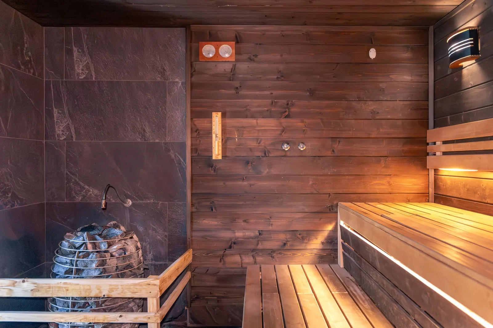 A sauna stove with stones beside wooden benches.