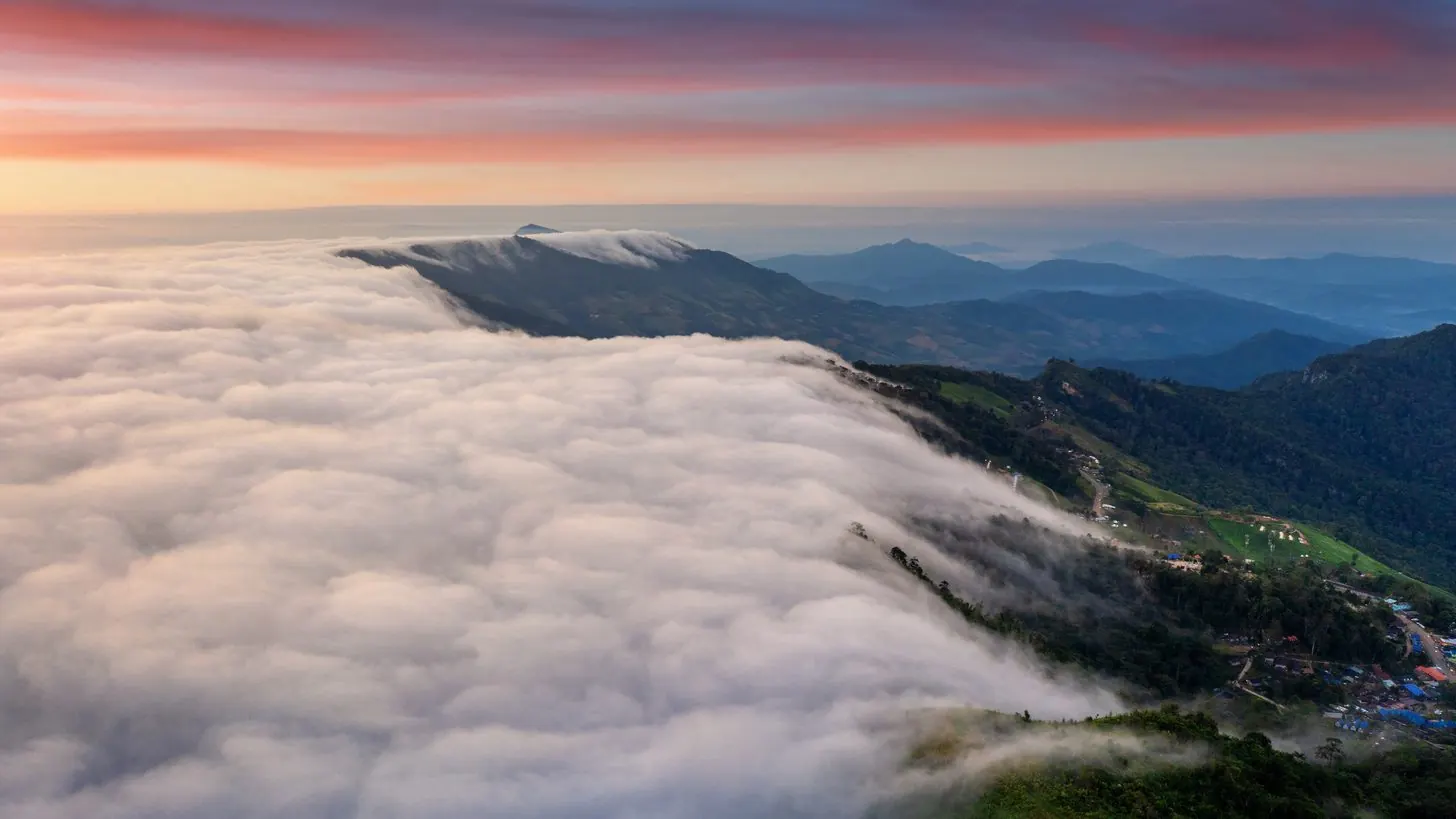 A sea of cloud below a mountain ridge at dawn.