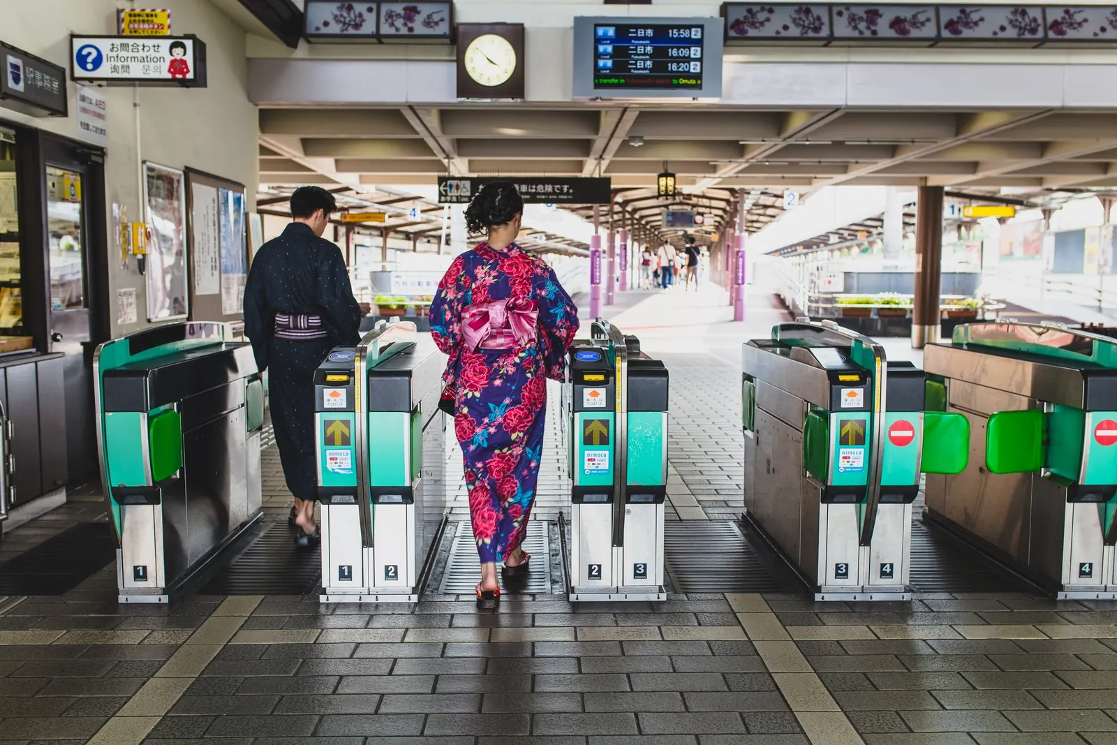 Travellers in kimono passing ticket gates at a station: rail is often the faster way across Kyoto.
