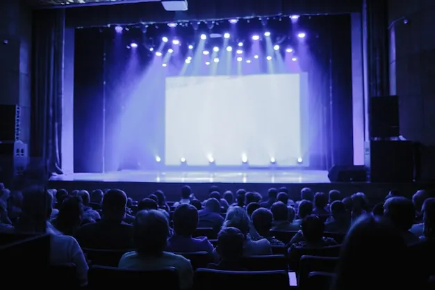 A theatre stage lit in blue with a seated audience in front of it.