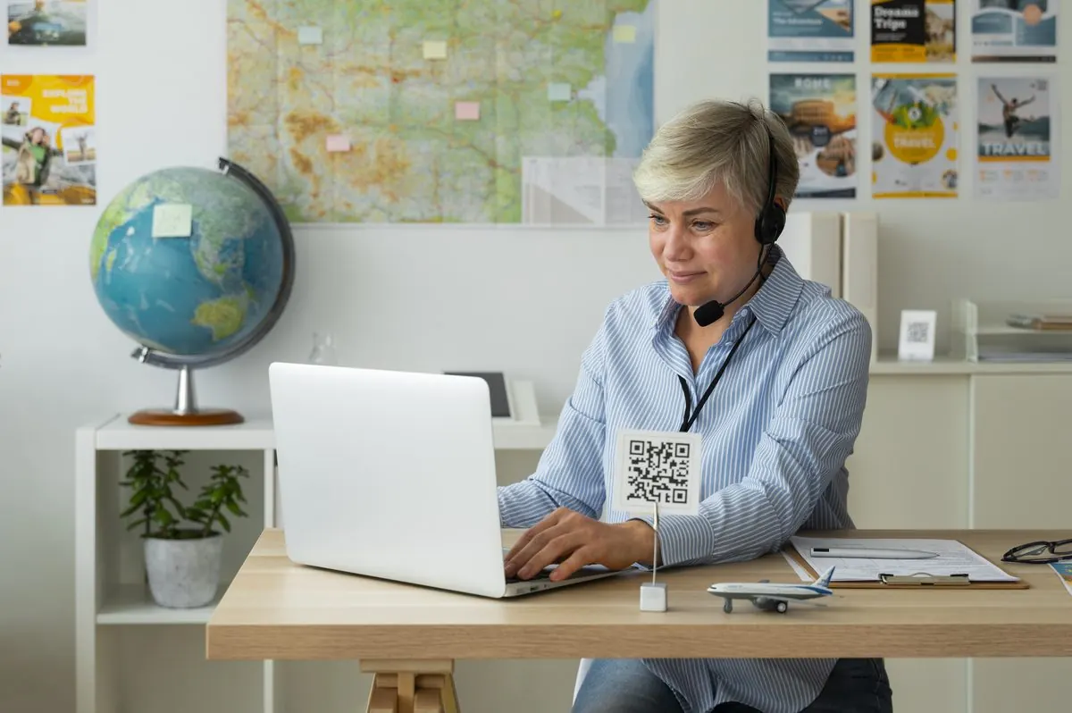 A travel agent with a headset working at a laptop.