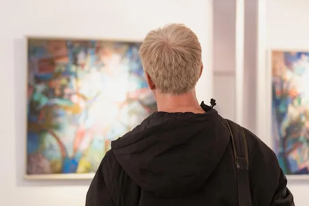 A man stands in front of a large colourful painting in a gallery.