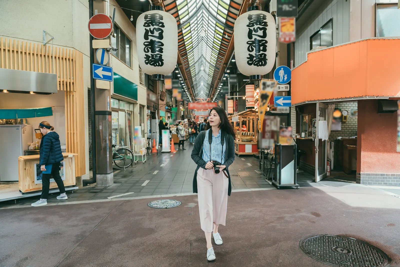 A visitor walking through a traditional market street in Japan.