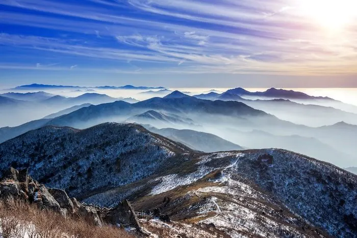 Mist lying between snow-dusted mountain ridges in winter.
