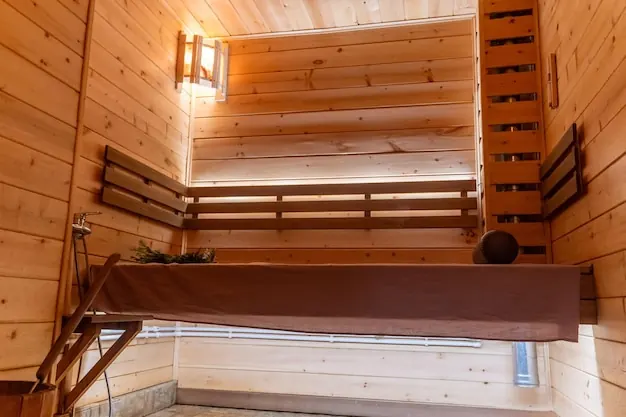A wooden sauna room with benches and soft wall lights.